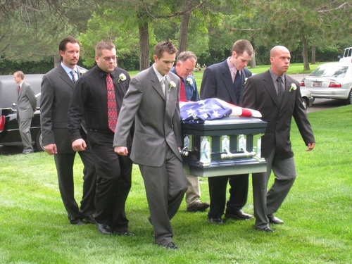 The pallbearers carry the casket to the grave site.