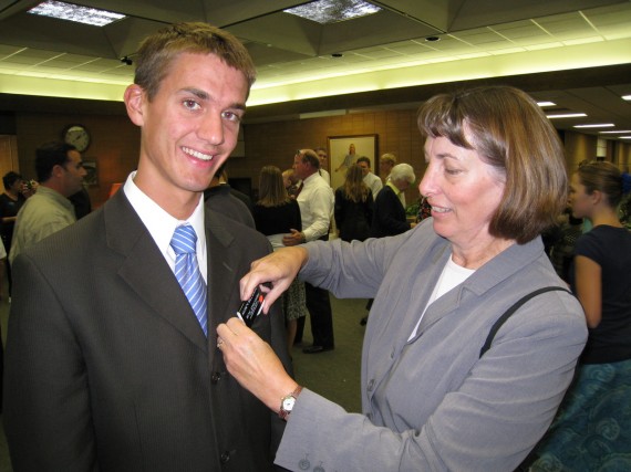 Jill places on Daniel his new missionary badge in the MTC foyer