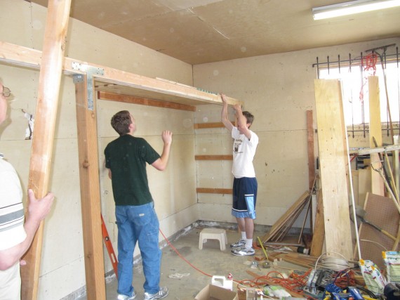 Paul and Jake install the first plywood sheet for the garage shelves